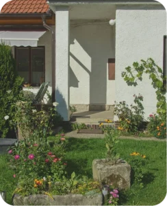 Zápraží domu s kvetoucím záhonem a kamennými korýtky